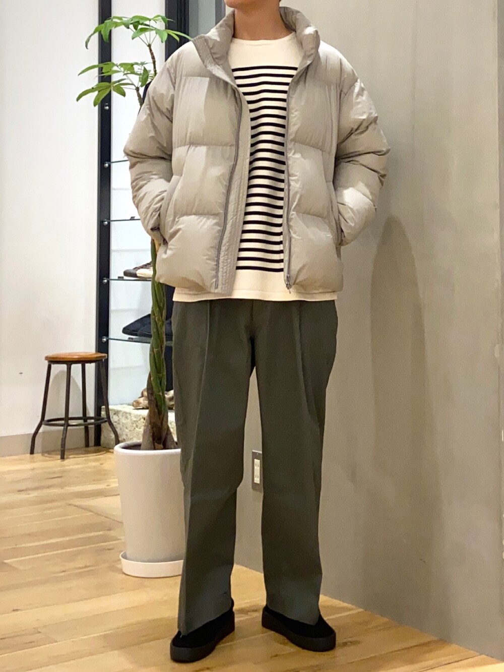 グレー系のダウンジャケット/コート、ホワイト系のニット/セーター、グリーン系のその他パンツを着用したメンズの秋コーディネートの2枚目の写真