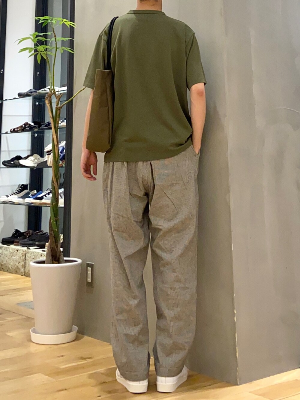 グリーン系のTシャツ/カットソー、ホワイト系のその他パンツ、ブラウン系のトートバッグを着用したメンズの春コーディネートの3枚目の写真