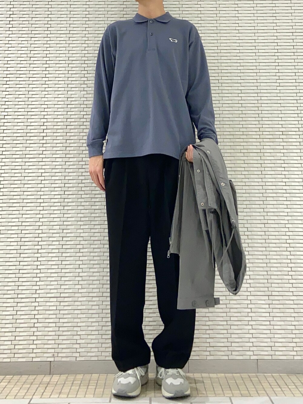 グレー系のマウンテンパーカー、ブルー系のポロシャツ、ブラック系のその他パンツを着用したメンズの春コーディネートの2枚目の写真