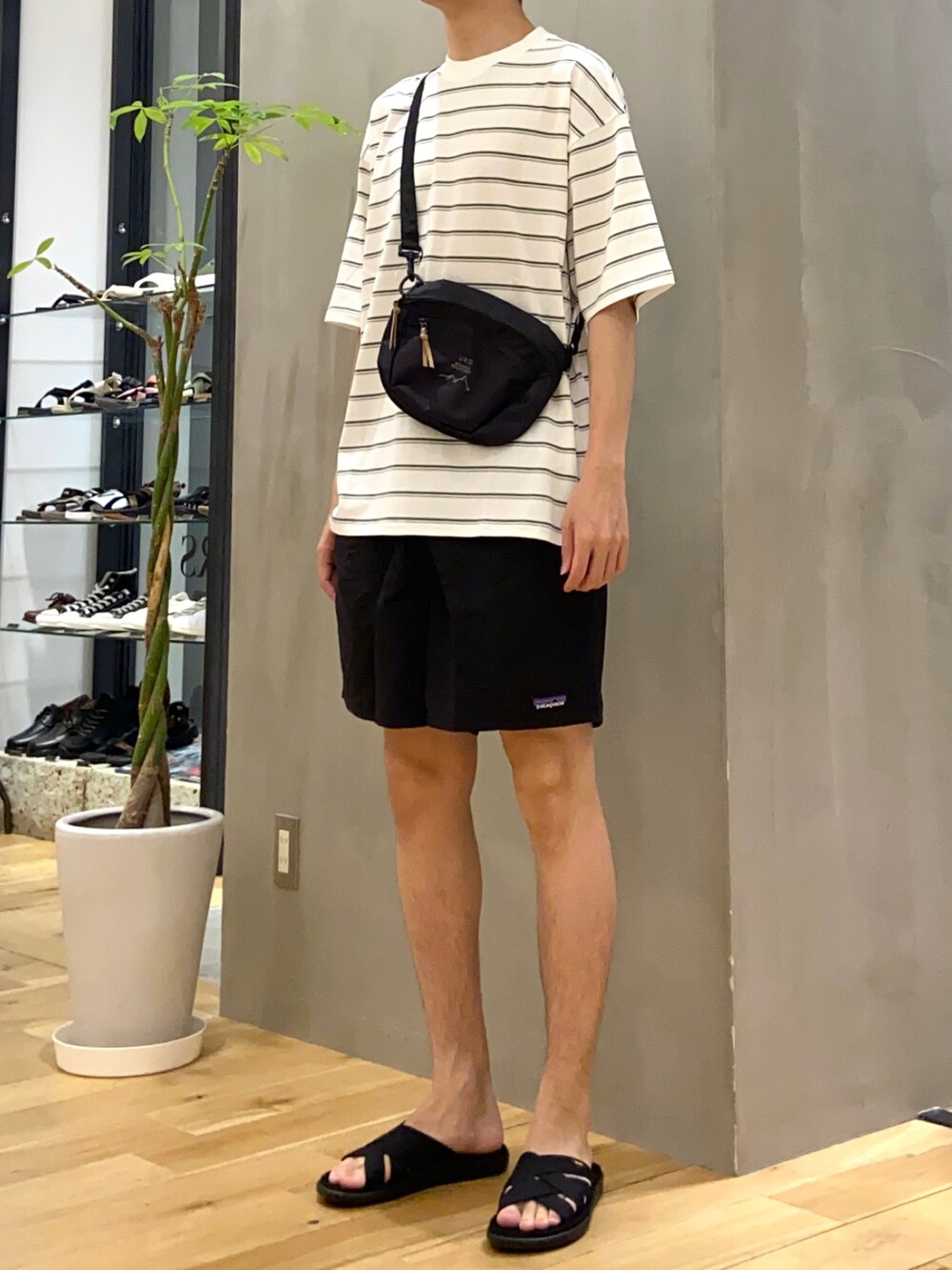 グリーン系のTシャツ/カットソー、ブラック系のショルダーバッグ、ブラック系のサンダルを着用したメンズの夏コーディネートの2枚目の写真