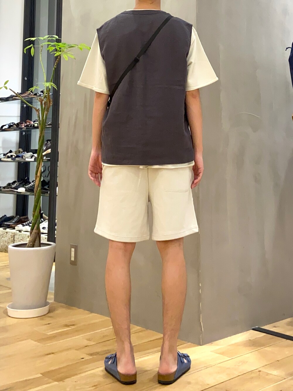 ブラック系のベスト、ホワイト系のショルダーバッグ、ブルー系のサンダルを着用したメンズの夏コーディネートの3枚目の写真