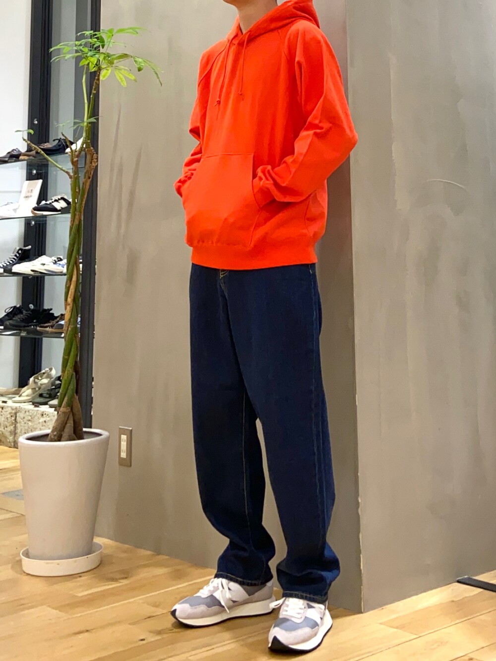 オレンジ系のパーカー、ブルー系のデニムパンツを着用したメンズの秋コーディネートの2枚目の写真