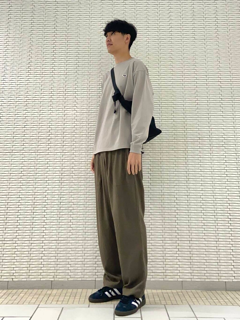 ブラック系のショルダーバッグ、ブラック系のスニーカー、グレー系のTシャツ/カットソーを着用したメンズの夏コーディネートの2枚目の写真