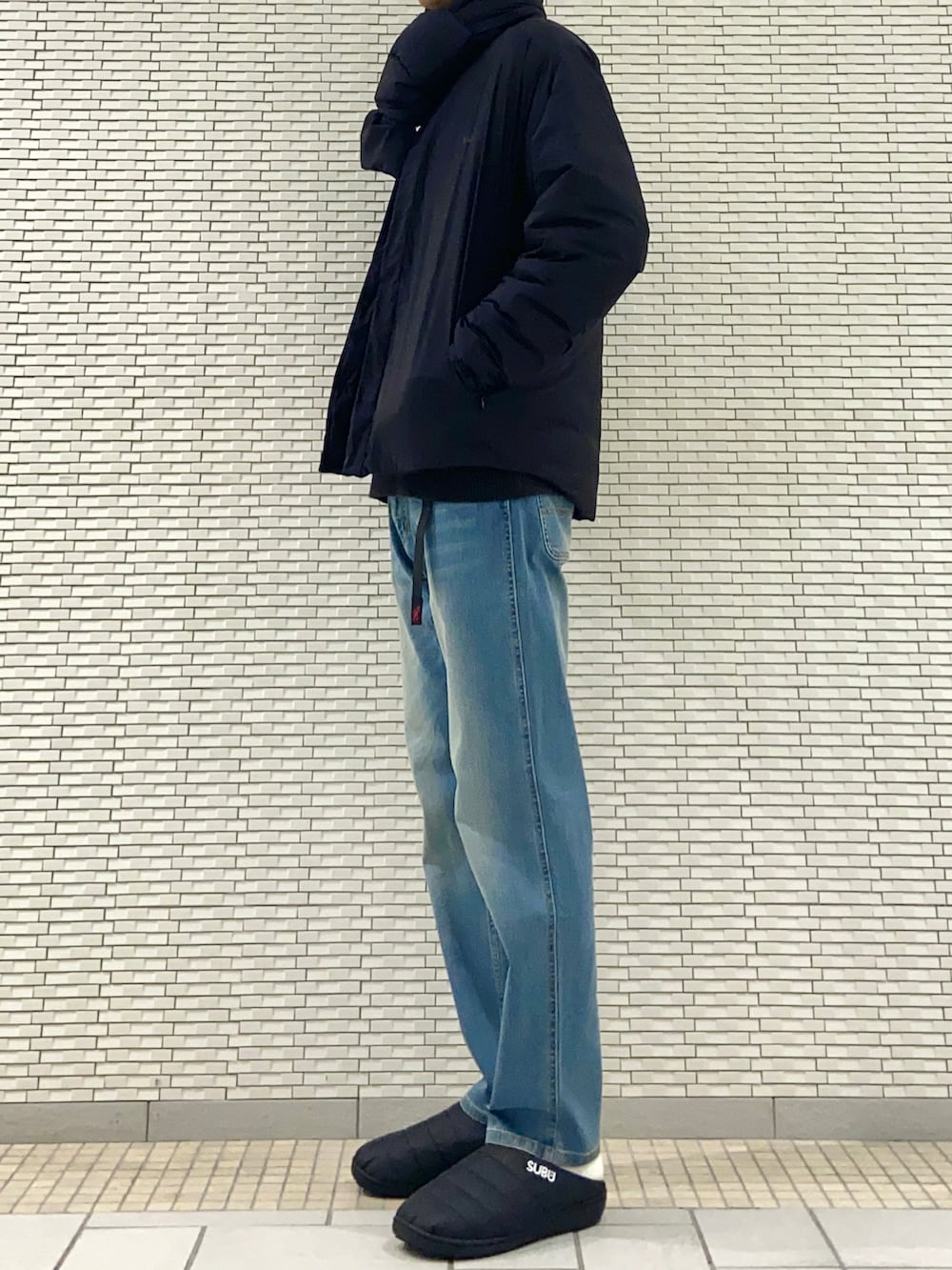 ブラック系のダウンジャケット/コート、グレー系のニット/セーター、ブルー系のその他パンツを着用したメンズの秋コーディネートの3枚目の写真