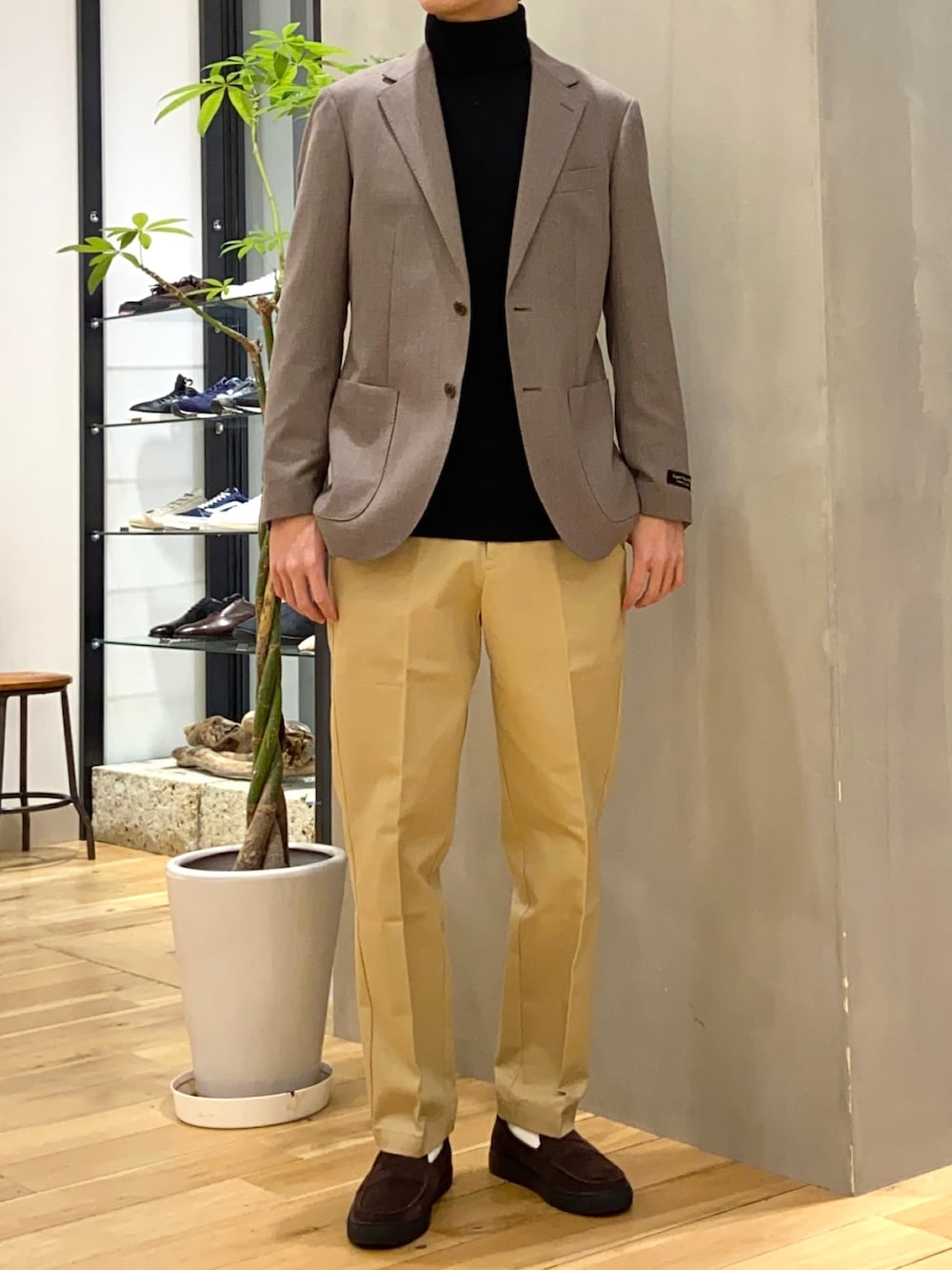 ブラウン系のスーツジャケット、ブラック系のニット/セーター、ブラウン系のローファーを着用したメンズの冬コーディネートの3枚目の写真