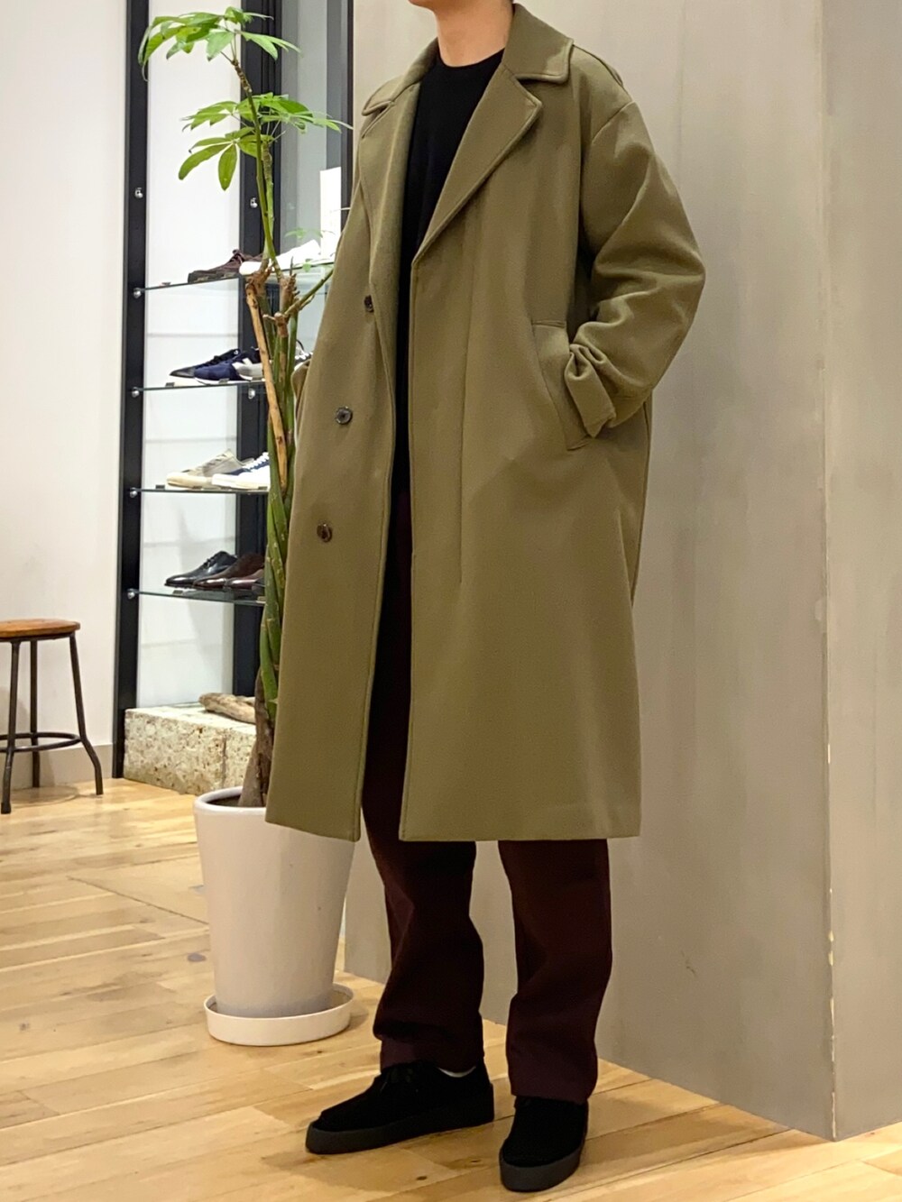 ブラック系のニット/セーター、グリーン系のチェスターコート、ブラック系のその他シューズを着用したメンズの冬コーディネートの2枚目の写真