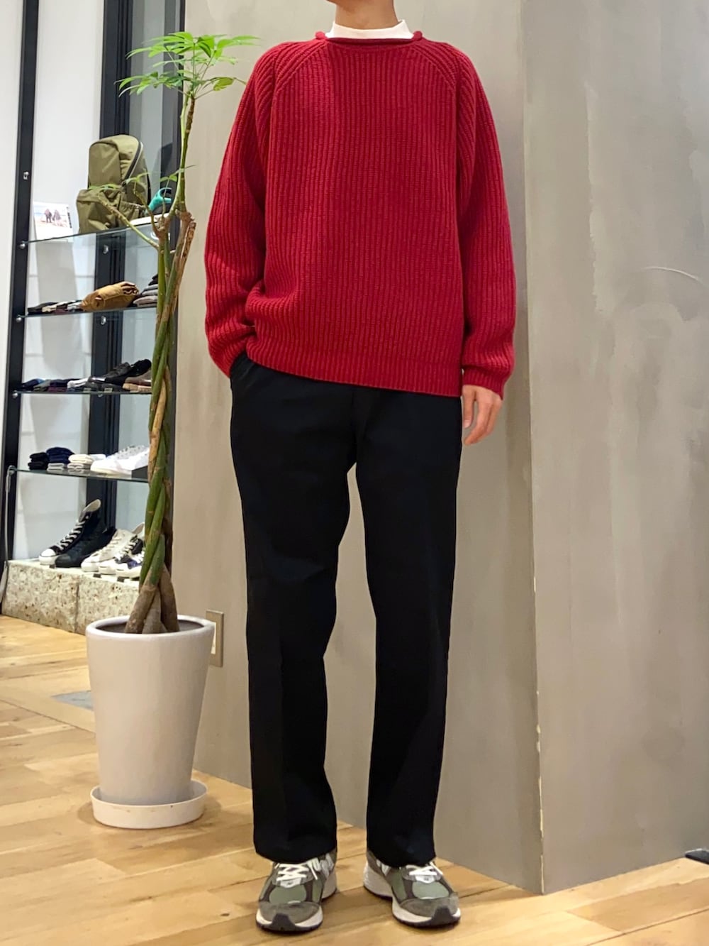 グレー系のダウンベスト、レッド系のニット/セーター、ブラック系のその他パンツを着用したメンズの冬コーディネートの2枚目の写真