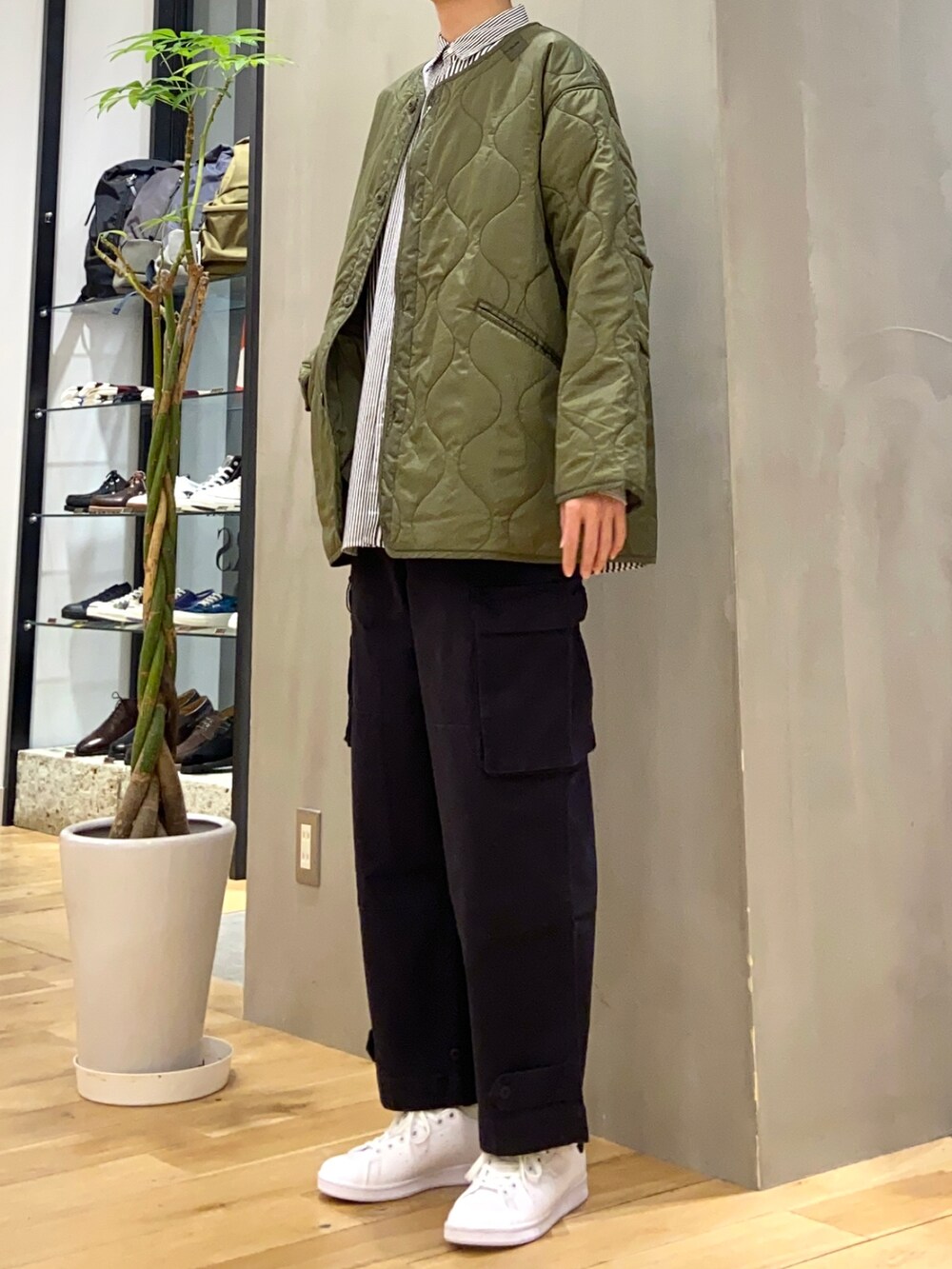 グリーン系のダウンジャケット/コート、ブルー系のシャツ/ブラウス、ブラック系のスニーカーを着用したメンズの冬コーディネートの3枚目の写真