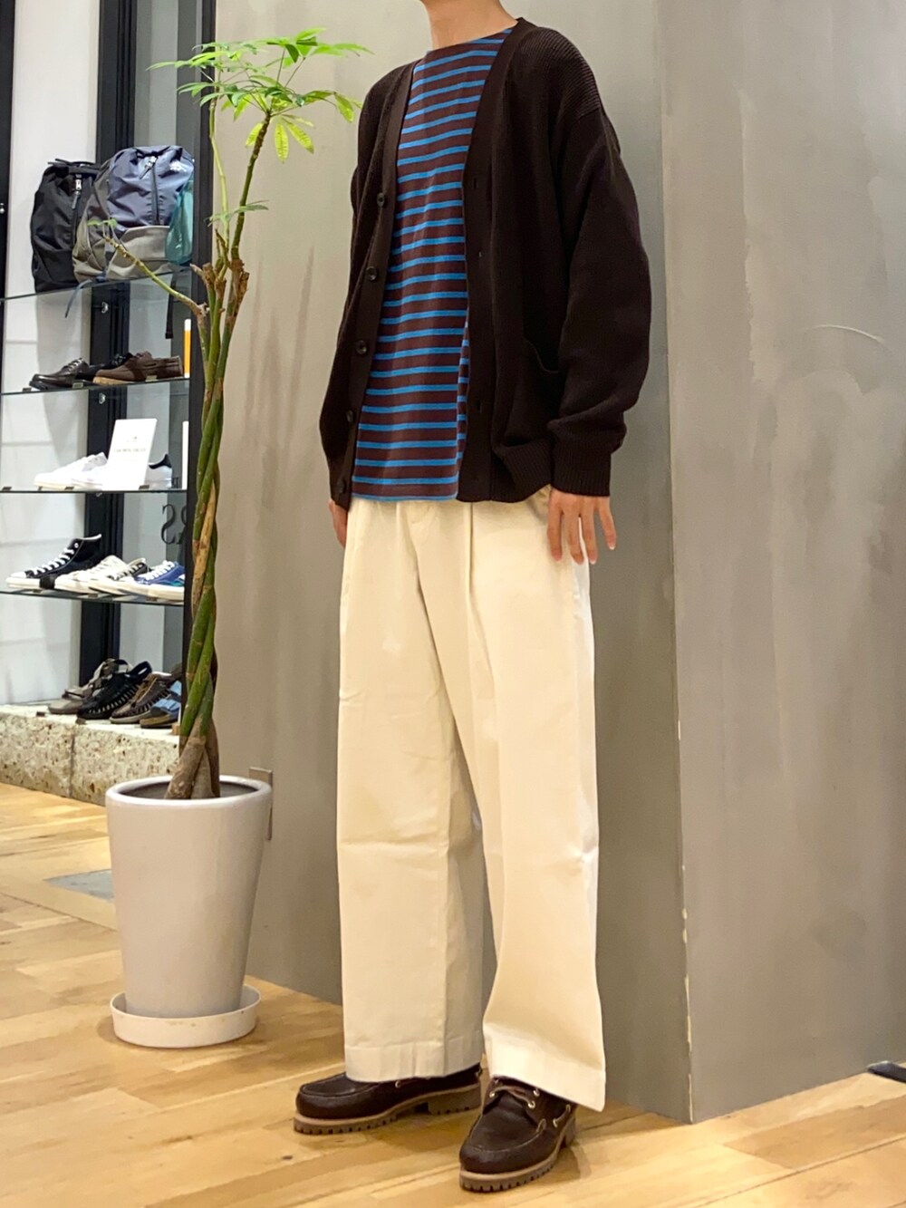 ブラウン系のカーディガン/ボレロ、ブラウン系のTシャツ/カットソー、ホワイト系のチノパンツを着用したメンズの秋コーディネートの2枚目の写真