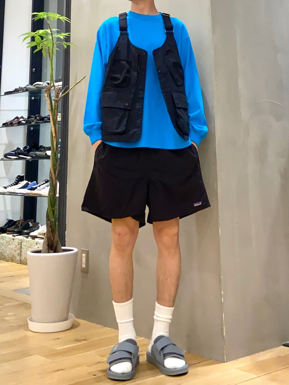 ブラック系のベスト、ブルー系のTシャツ/カットソー、グレー系のサンダルを着用したメンズの春コーディネートの3枚目の写真