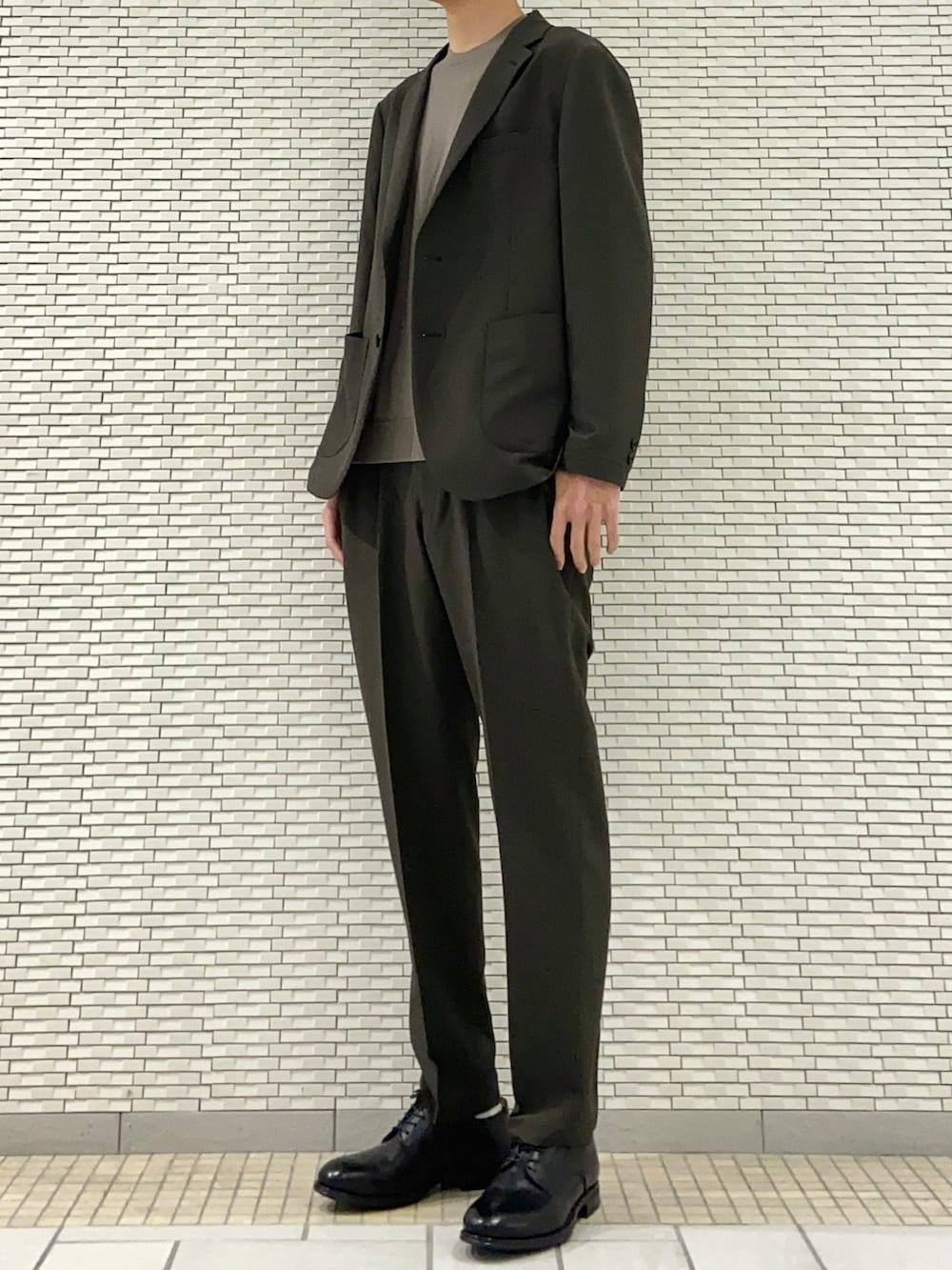 グリーン系のスーツジャケット、ブラウン系のニット/セーター、グリーン系のスーツパンツを着用したメンズの春コーディネートの2枚目の写真