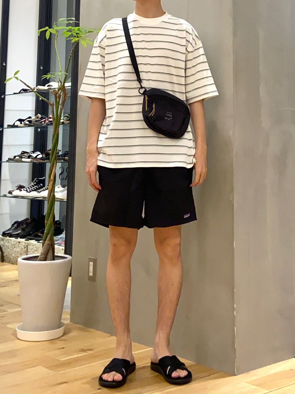 グリーン系のTシャツ/カットソー、ブラック系のショルダーバッグ、ブラック系のサンダルを着用したメンズの夏コーディネートの3枚目の写真