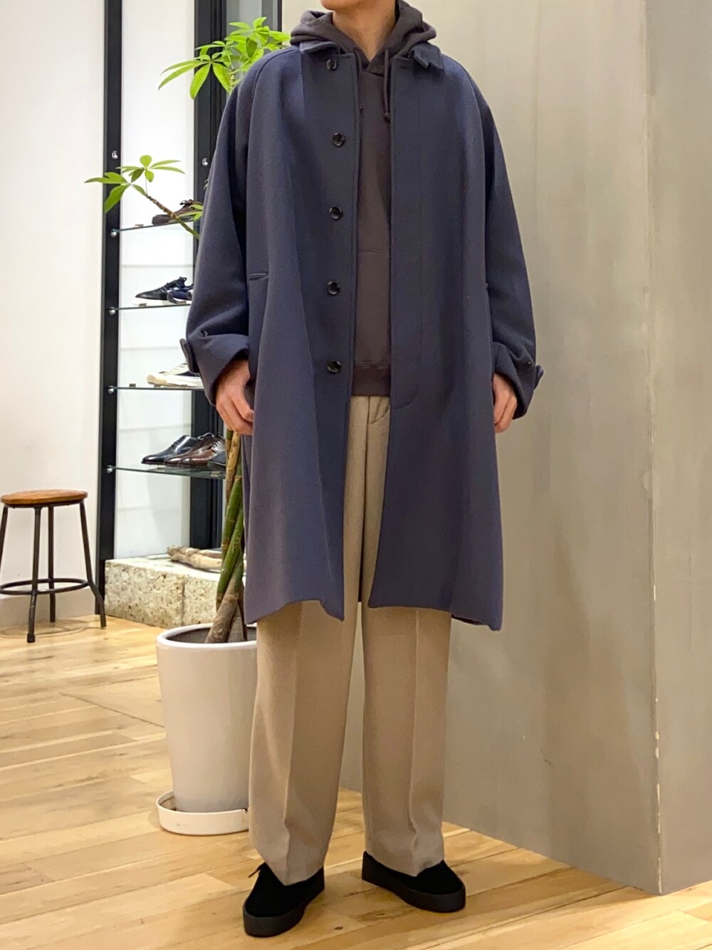 ブルー系のステンカラーコート、グレー系のパーカー、ベージュ系のその他パンツを着用したメンズの冬コーディネートの3枚目の写真