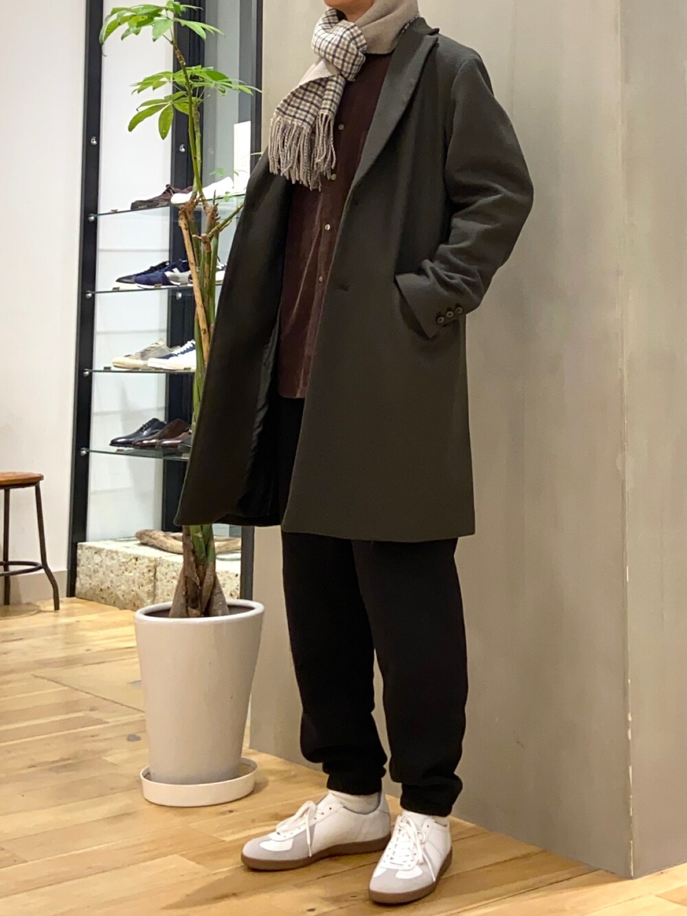 ブラック系のチェスターコート、ブラウン系のシャツ/ブラウス、ホワイト系のスニーカーを着用したメンズの冬コーディネートの2枚目の写真