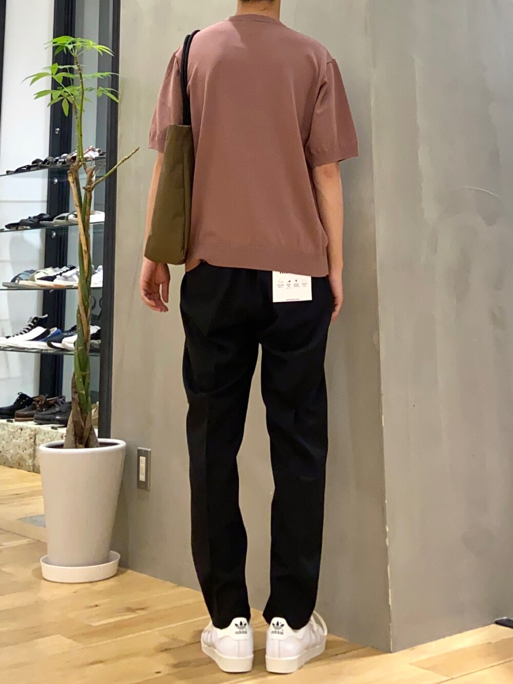 ピンク系のニット/セーター、ブラック系のその他パンツ、ブラウン系のトートバッグを着用したメンズの春コーディネートの3枚目の写真