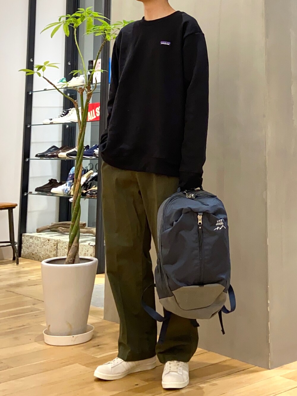 グリーン系のチノパンツ、ブルー系のバックパック/リュック、ベージュ系のスニーカーを着用したメンズの冬コーディネートの4枚目の写真