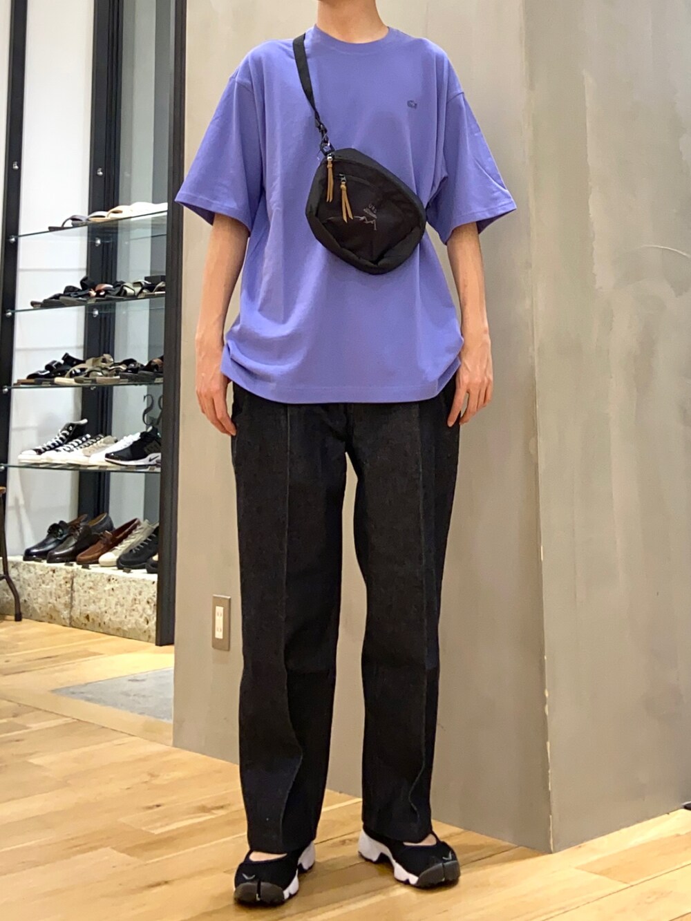 パープル系のTシャツ/カットソー、ブラック系のショルダーバッグ、ブルー系のデニムパンツを着用したメンズの春コーディネートの3枚目の写真