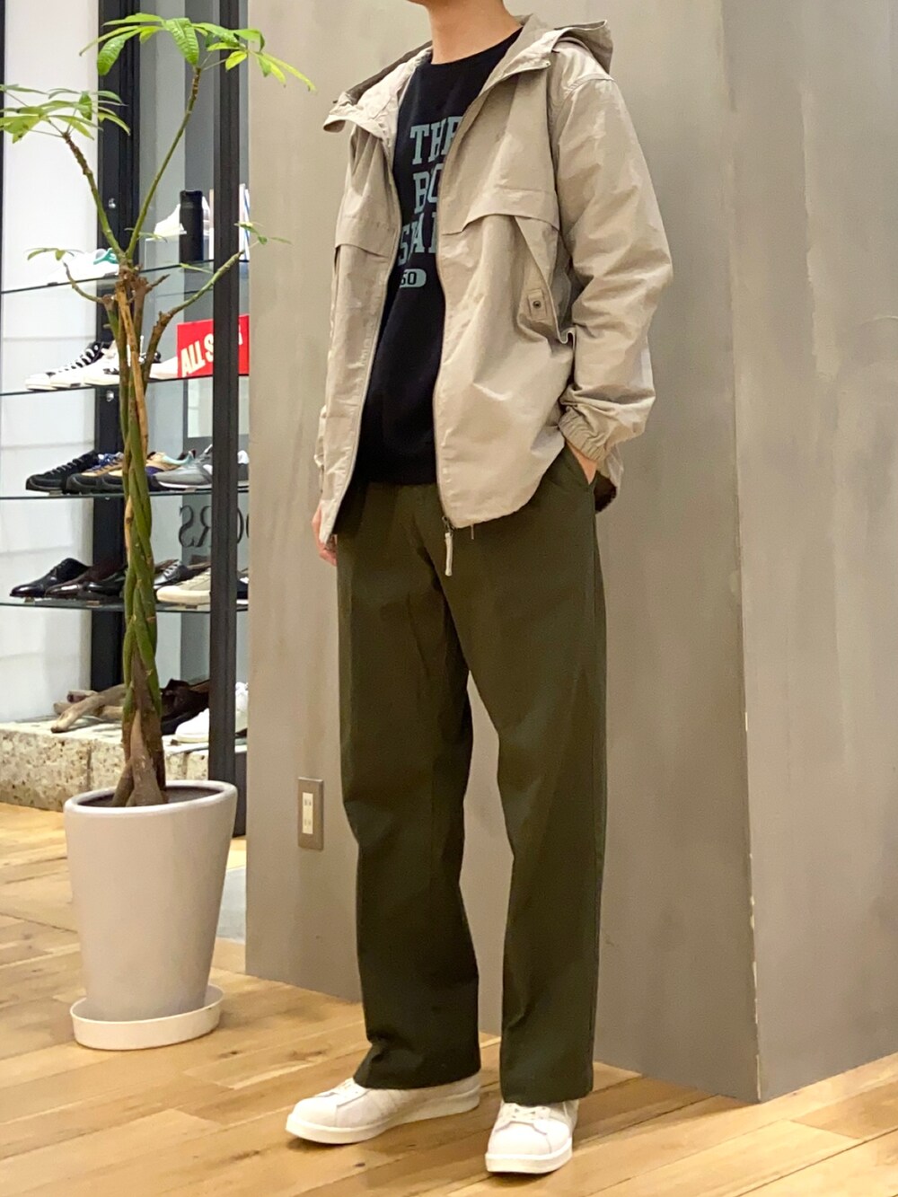 ベージュ系のマウンテンパーカー、ブラック系のスウェット、グリーン系のチノパンツを着用したメンズの春コーディネートの4枚目の写真