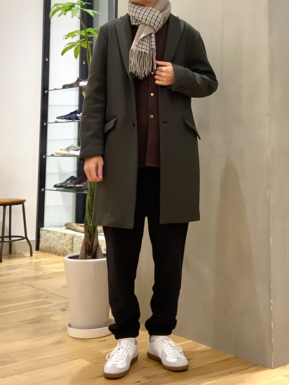 ブラック系のチェスターコート、ブラウン系のシャツ/ブラウス、ホワイト系のスニーカーを着用したメンズの冬コーディネートの3枚目の写真