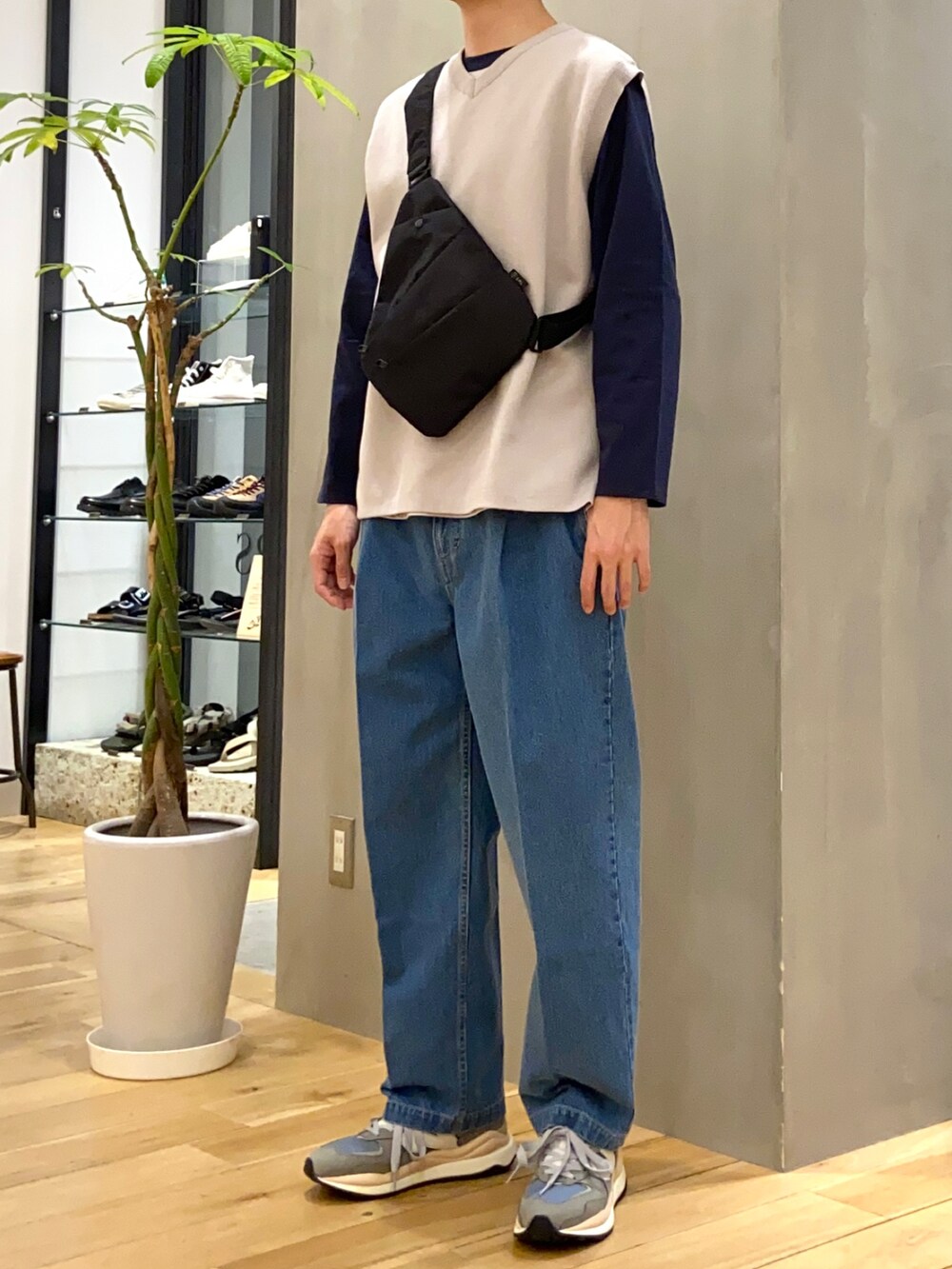 グレー系のベスト、ブルー系のTシャツ/カットソー、ブラック系のショルダーバッグを着用したメンズの春コーディネートの2枚目の写真