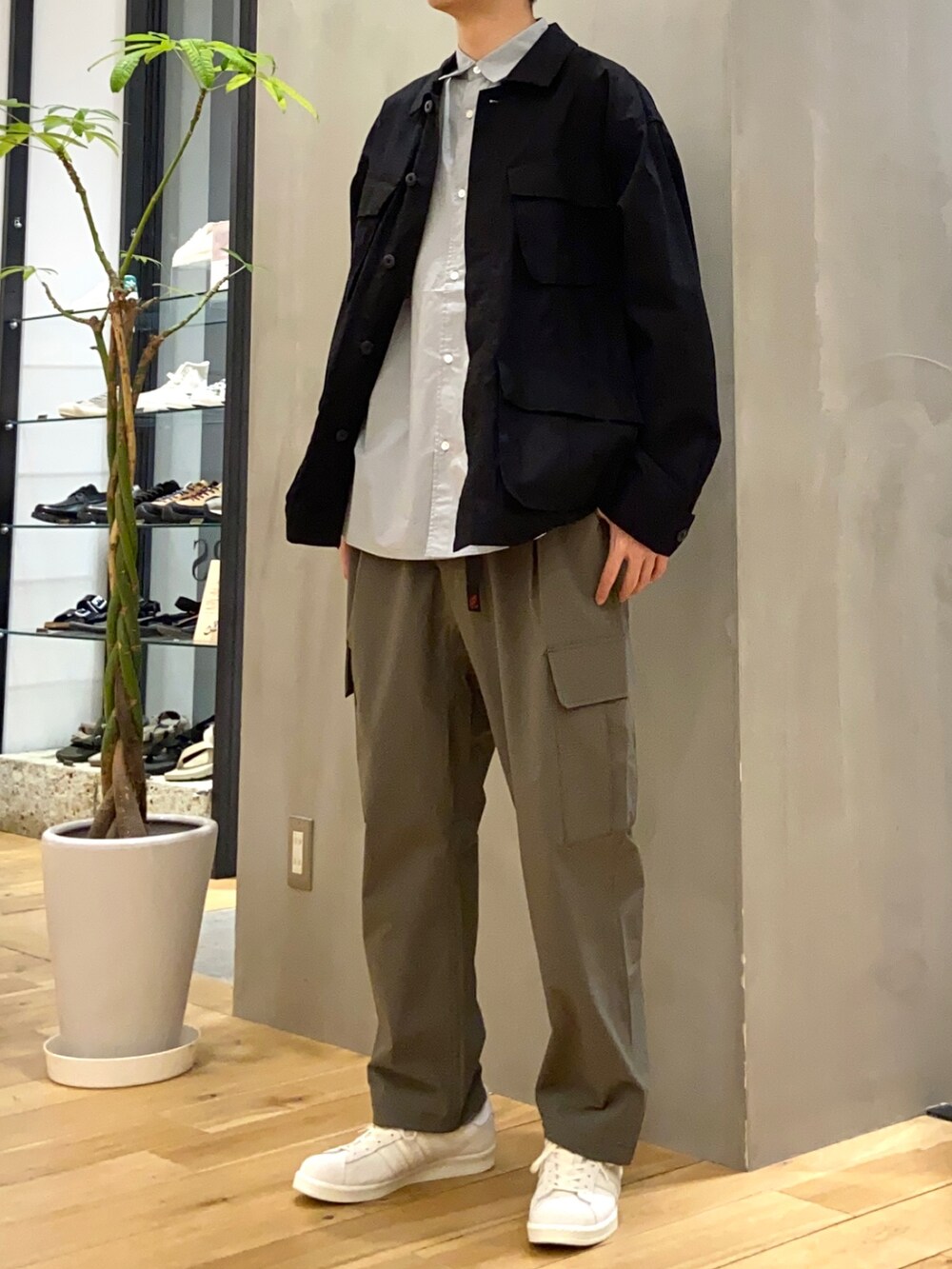 ブラック系のミリタリージャケット、ブルー系のシャツ/ブラウス、ベージュ系のスニーカーを着用したメンズの春コーディネートの3枚目の写真