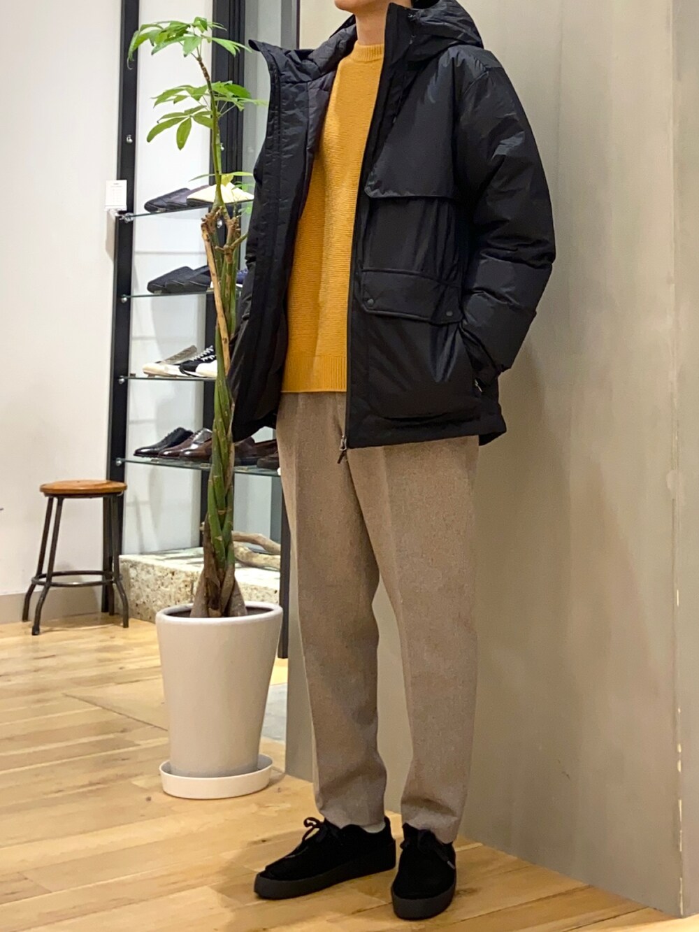 ブラック系のダウンジャケット/コート、イエロー系のニット/セーター、ブラック系のその他シューズを着用したメンズの冬コーディネートの3枚目の写真