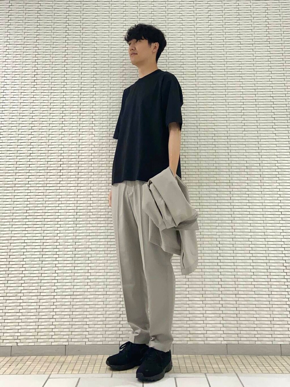 ベージュ系のその他パンツ、ブラック系のTシャツ/カットソー、ブラック系のスニーカーを着用したメンズの夏コーディネートの2枚目の写真