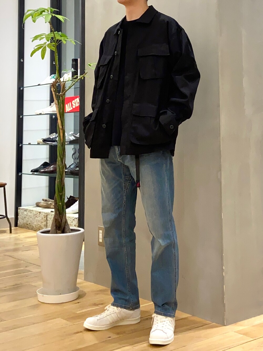 ブラック系のミリタリージャケット、ブラック系のニット/セーター、ブルー系のその他パンツを着用したメンズの春コーディネートの2枚目の写真