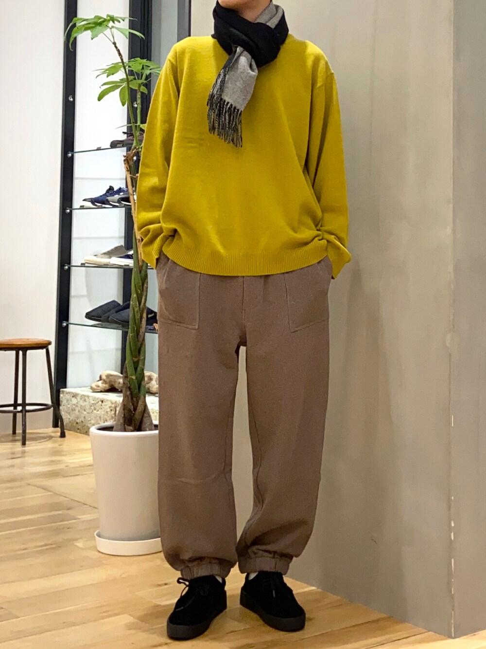 ホワイト系のステンカラーコート、イエロー系のニット/セーター、ブラック系のその他シューズを着用したメンズの秋コーディネートの2枚目の写真