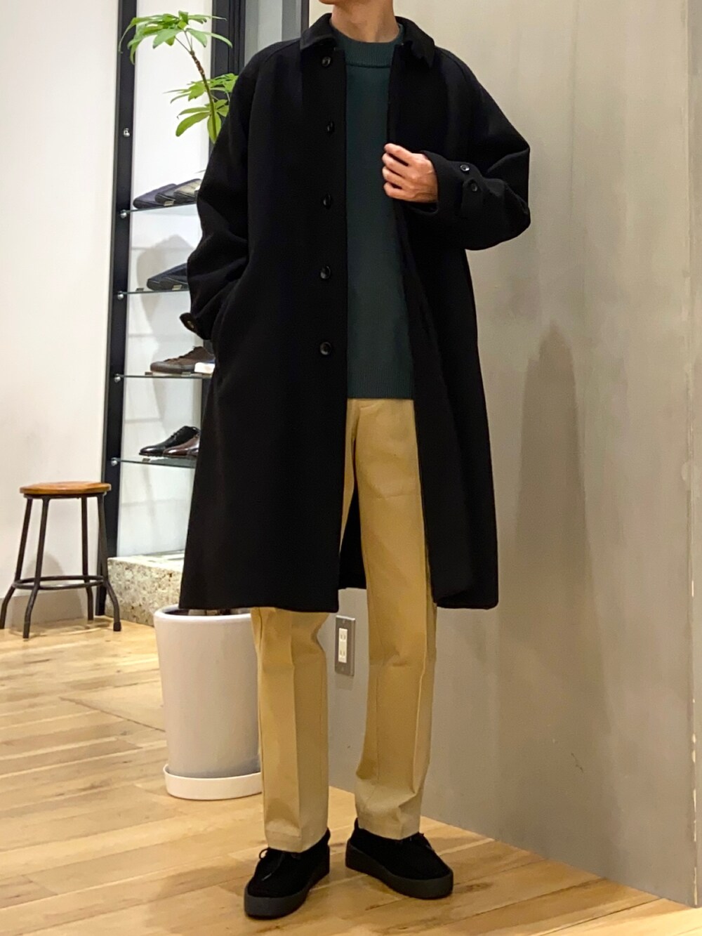 ブラック系のステンカラーコート、グリーン系のニット/セーター、ベージュ系のその他パンツを着用したメンズの冬コーディネートの3枚目の写真