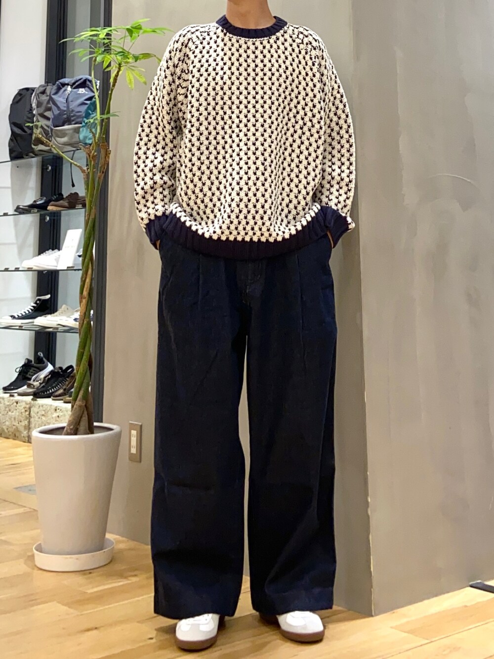 ホワイト系のニット/セーター、ブルー系のデニムパンツ、ホワイト系のスニーカーを着用したメンズの秋コーディネートの2枚目の写真