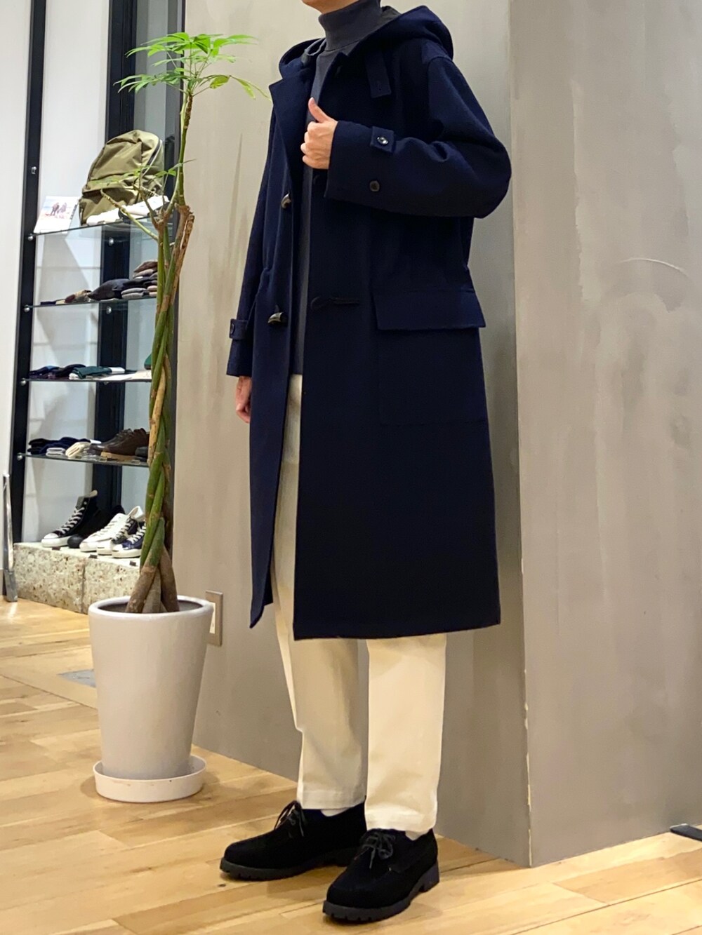 ブルー系のダッフルコート、グレー系のニット/セーター、ホワイト系のチノパンツを着用したメンズの秋コーディネートの2枚目の写真