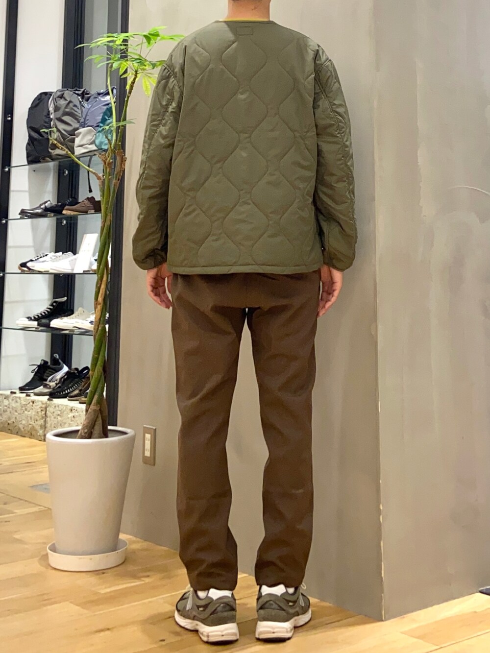 グリーン系のダウンジャケット/コート、イエロー系のニット/セーター、ブラウン系のその他パンツを着用したメンズの秋コーディネートの3枚目の写真