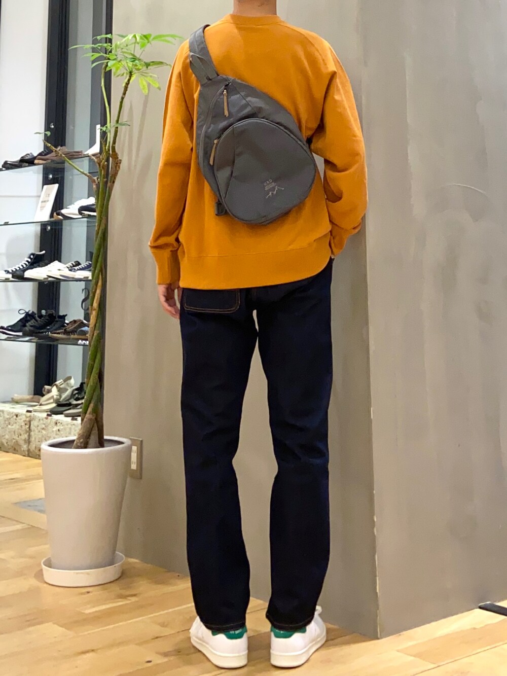 オレンジ系のスウェット、グレー系のショルダーバッグ、ブルー系のその他パンツを着用したメンズの秋コーディネートの3枚目の写真