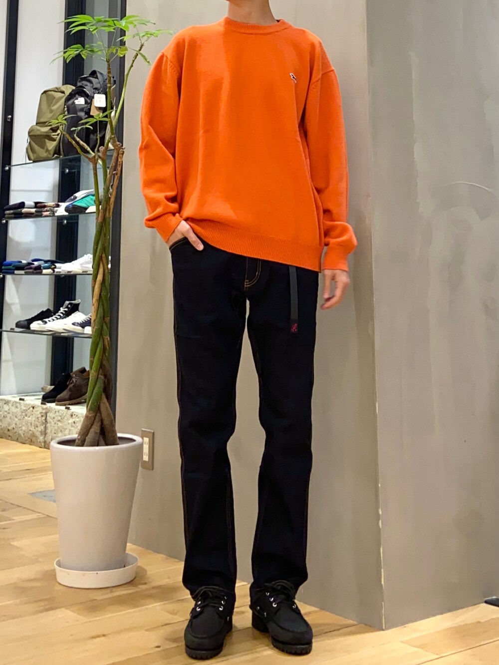 ブラック系のダウンジャケット/コート、オレンジ系のニット/セーター、ブルー系のその他パンツを着用したメンズの冬コーディネートの2枚目の写真