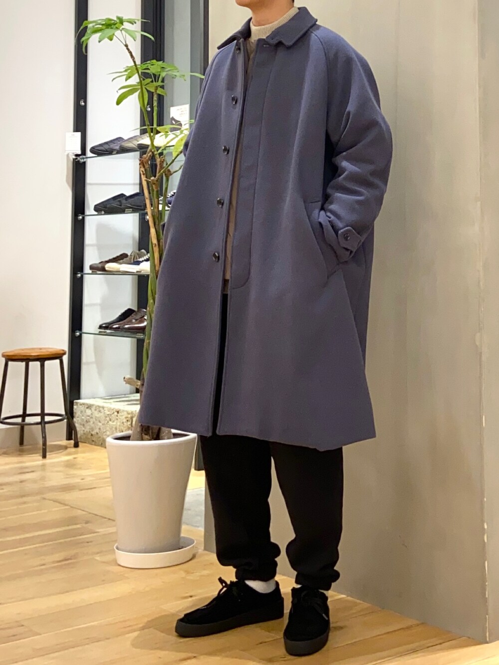 ブルー系のステンカラーコート、ベージュ系のニット/セーター、ブラウン系のダウンジャケット/コートを着用したメンズの冬コーディネートの4枚目の写真