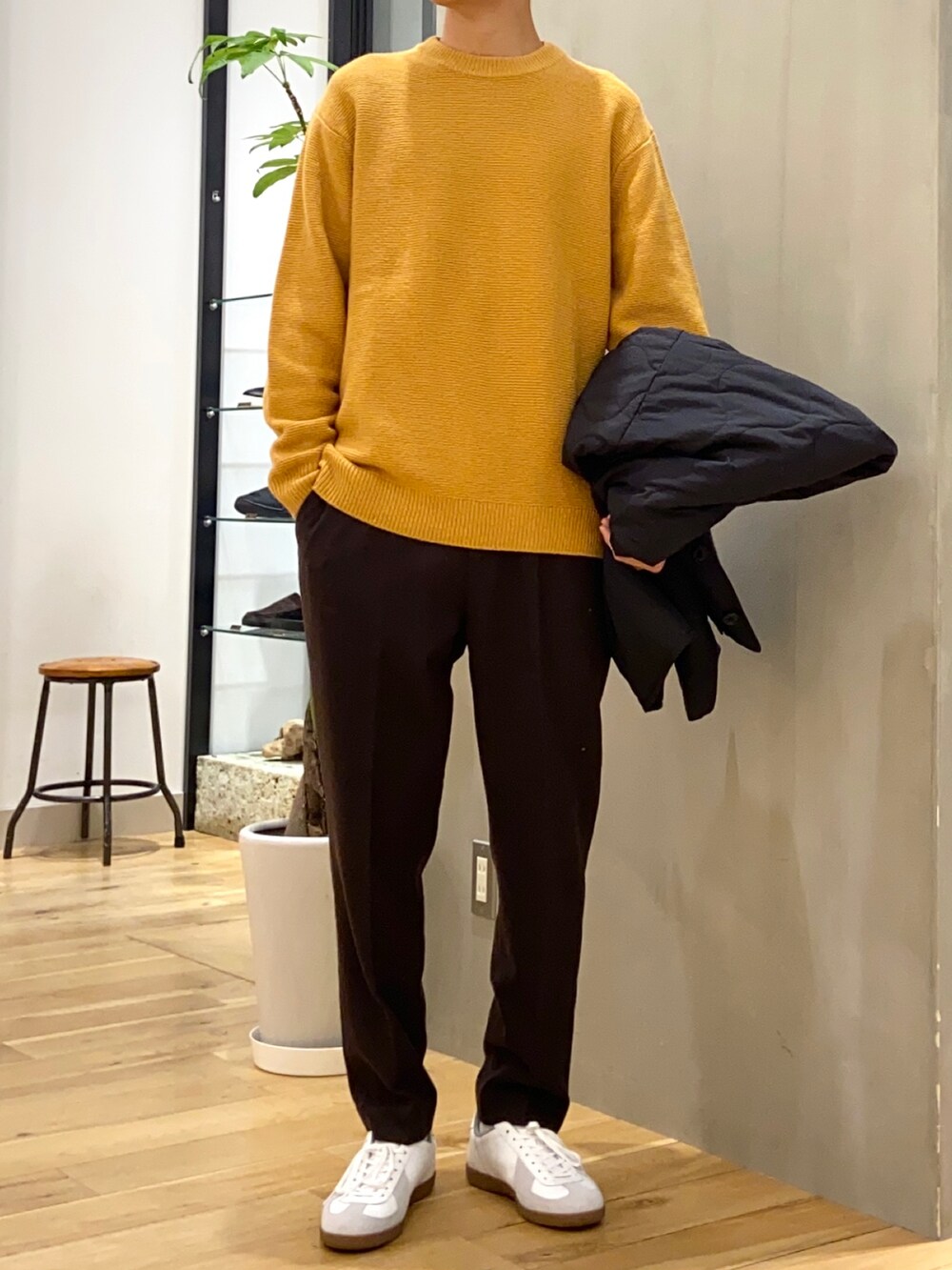 ブラック系のブルゾン、イエロー系のニット/セーター、ホワイト系のスニーカーを着用したメンズの秋コーディネートの2枚目の写真