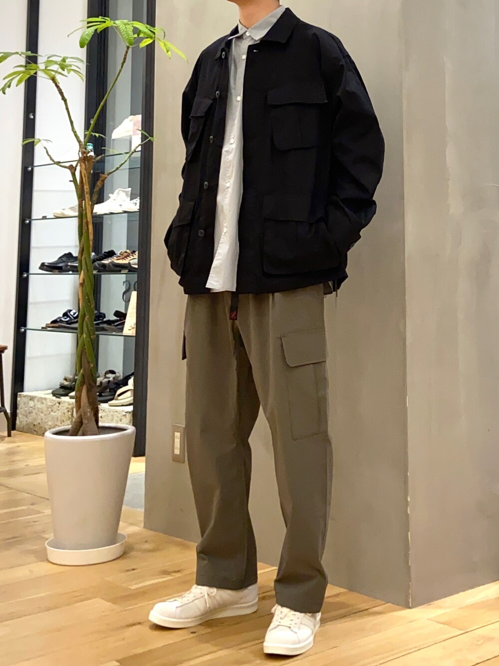 ブラック系のミリタリージャケット、ブルー系のシャツ/ブラウス、ベージュ系のスニーカーを着用したメンズの春コーディネートの5枚目の写真