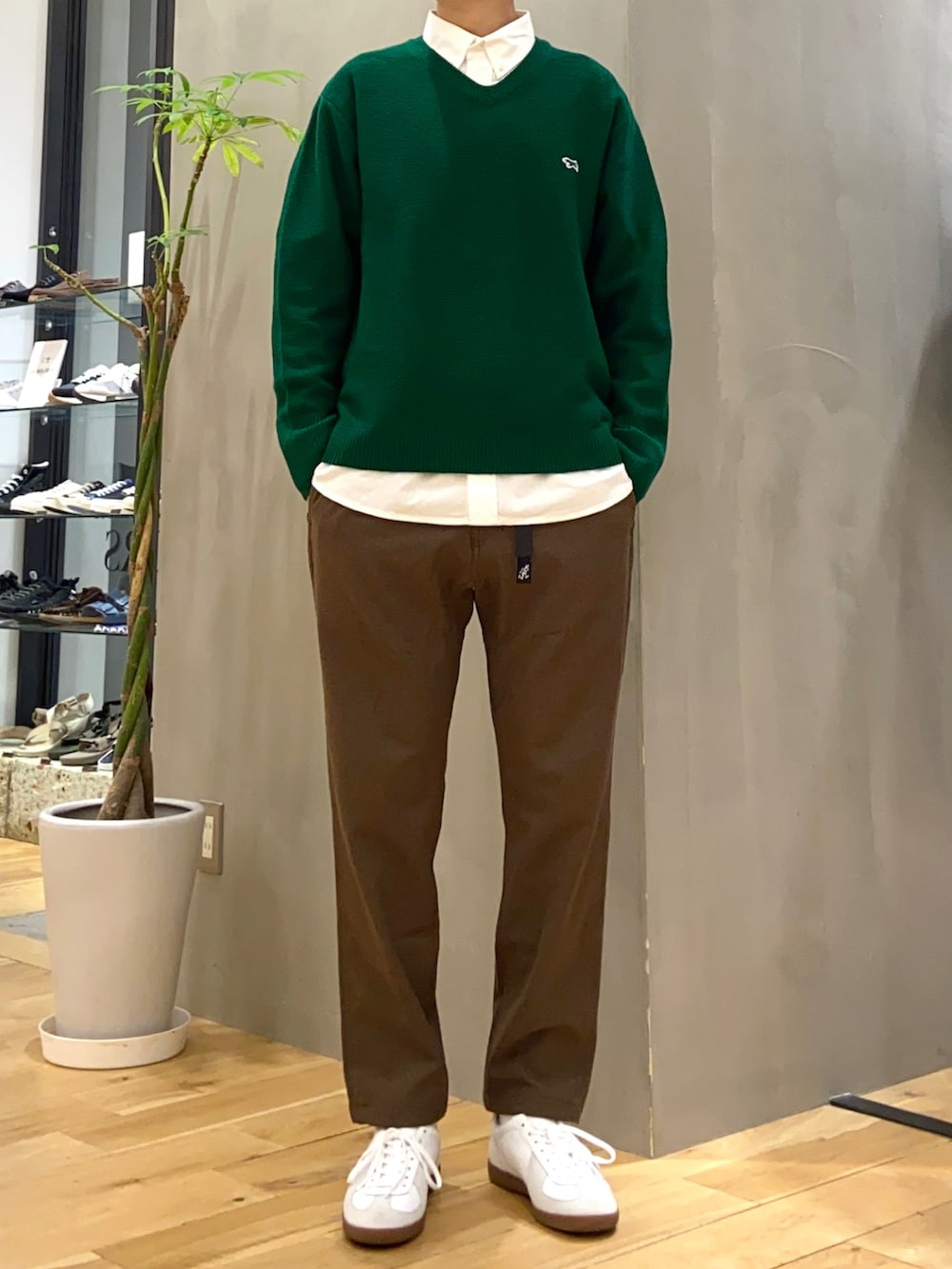 グリーン系のニット/セーター、ホワイト系のシャツ/ブラウス、ホワイト系のスニーカーを着用したメンズの秋コーディネートの2枚目の写真