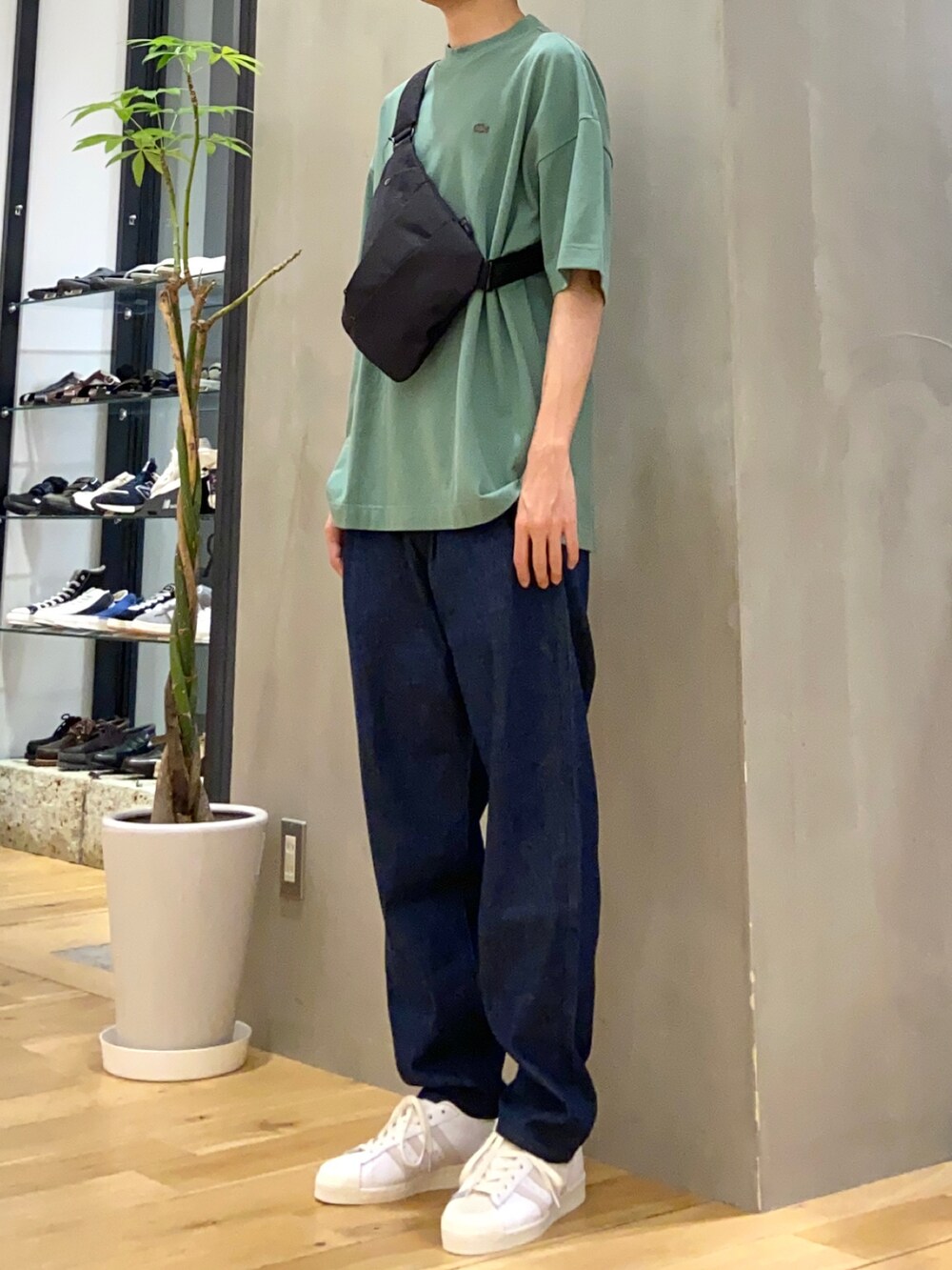 グリーン系のTシャツ/カットソー、ブラック系のショルダーバッグ、ブルー系のデニムパンツを着用したメンズの春コーディネートの2枚目の写真