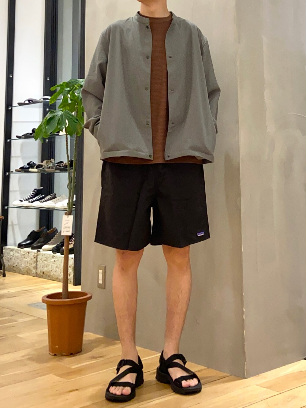 グリーン系のブルゾン、オレンジ系のTシャツ/カットソー、ブラック系のサンダルを着用したメンズの夏コーディネートの3枚目の写真