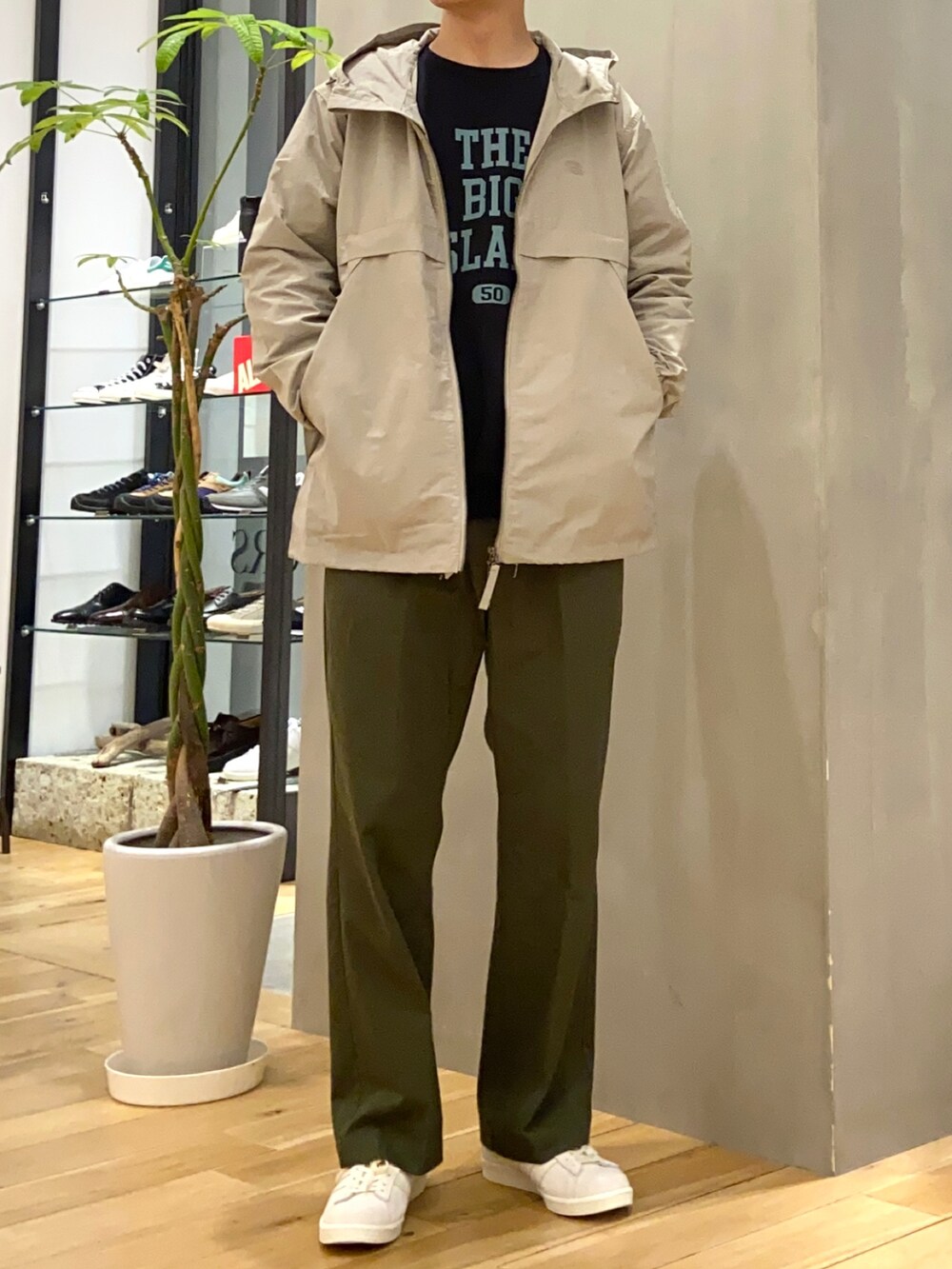 ベージュ系のマウンテンパーカー、ブラック系のスウェット、グリーン系のチノパンツを着用したメンズの春コーディネートの3枚目の写真