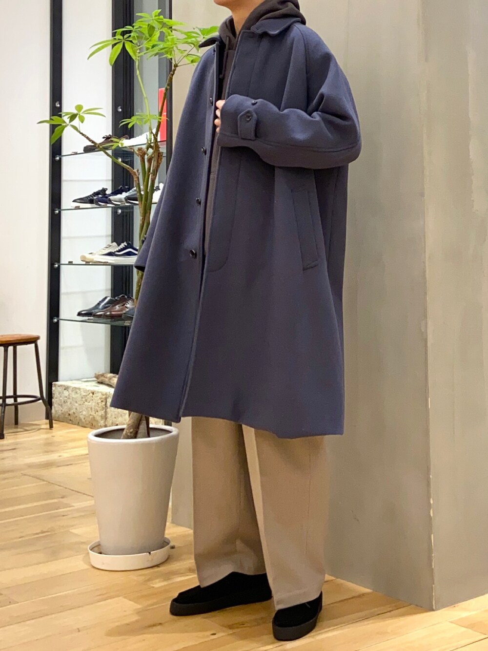 ブルー系のステンカラーコート、グレー系のパーカー、ベージュ系のその他パンツを着用したメンズの冬コーディネートの2枚目の写真