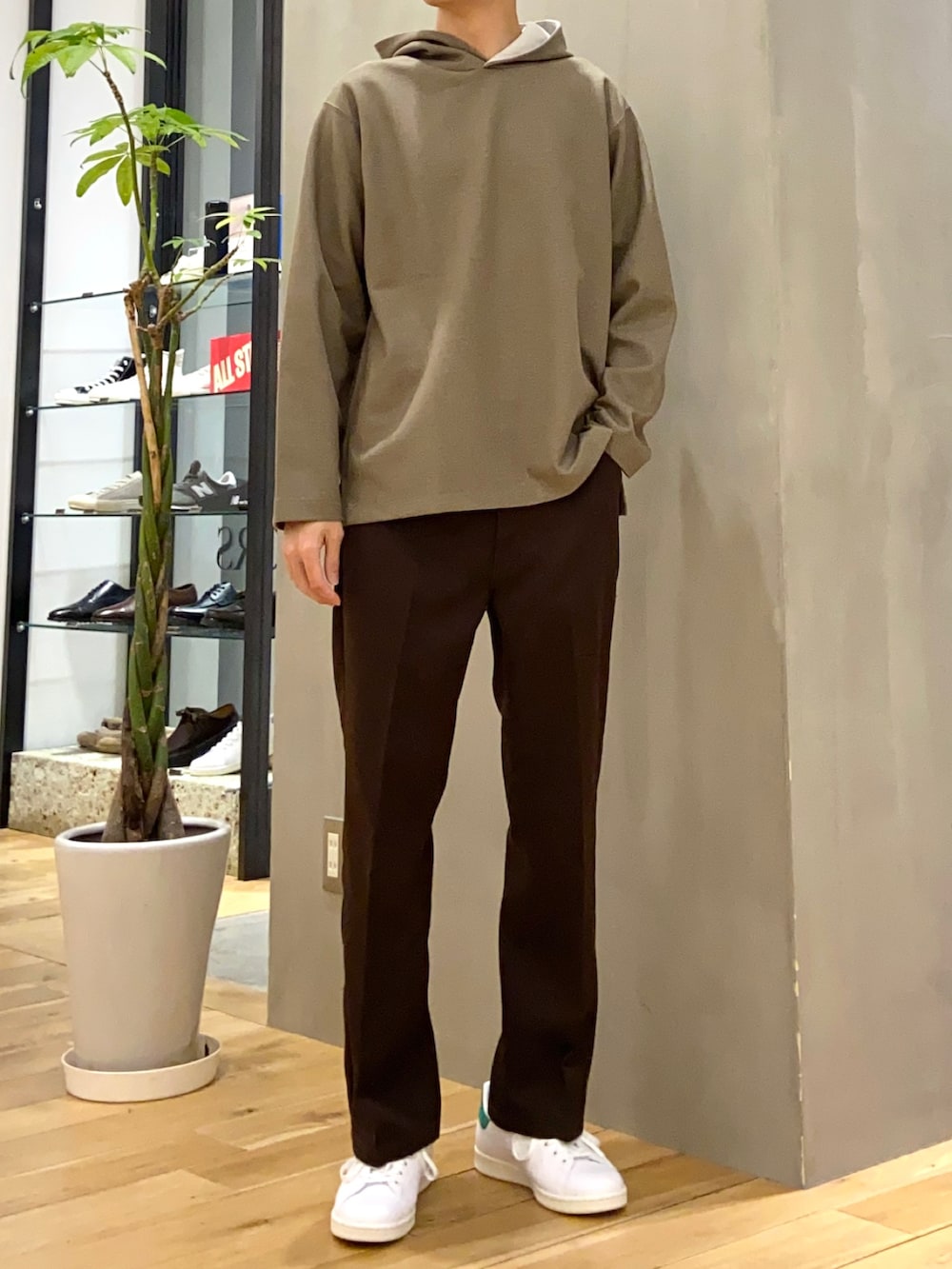 グレー系のステンカラーコート、グリーン系のパーカー、ブラウン系のその他パンツを着用したメンズの春コーディネートの2枚目の写真