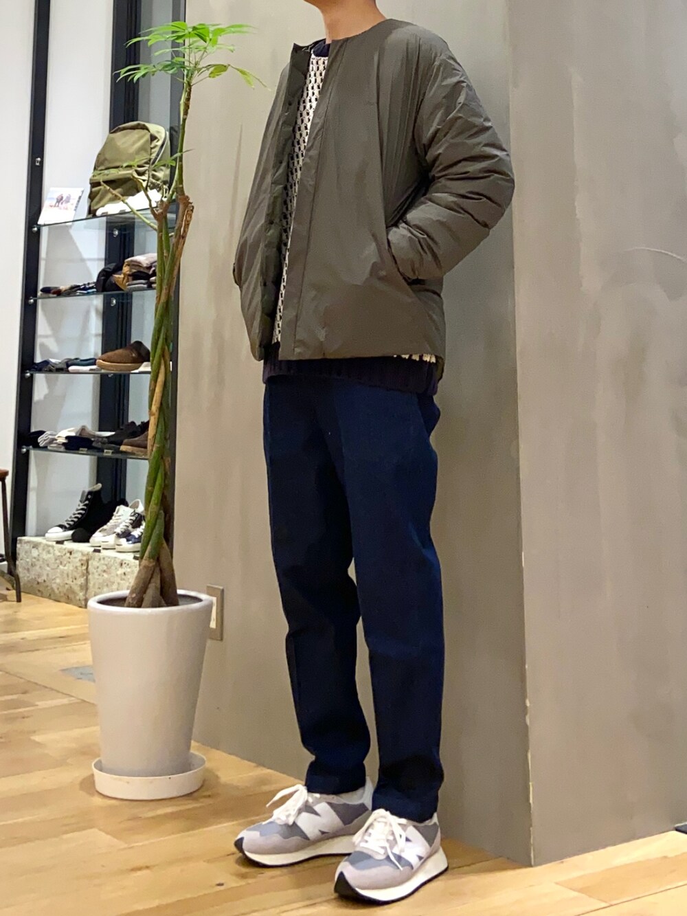 グリーン系のダウンジャケット/コート、ホワイト系のニット/セーター、ブルー系のデニムパンツを着用したメンズの秋コーディネートの3枚目の写真