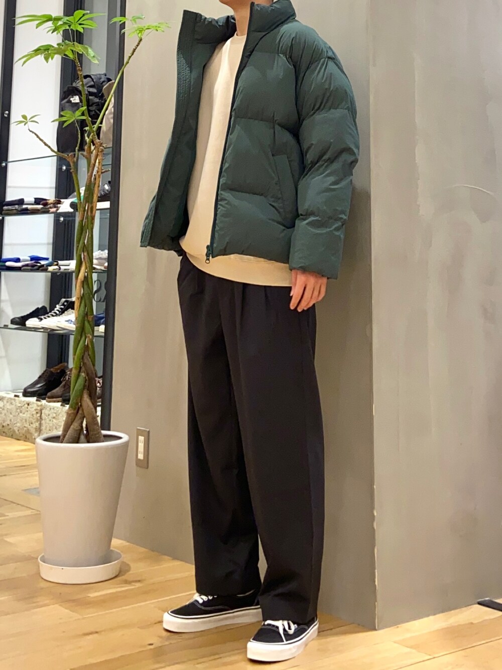 グリーン系のダウンジャケット/コート、ベージュ系のスウェット、ブラック系のスニーカーを着用したメンズの冬コーディネートの3枚目の写真