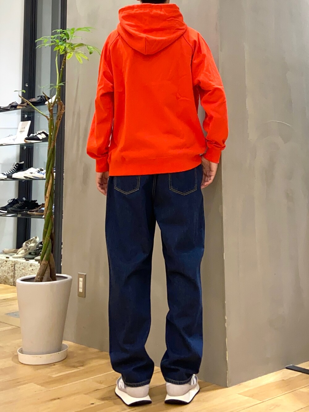 オレンジ系のパーカー、ブルー系のデニムパンツを着用したメンズの秋コーディネートの3枚目の写真