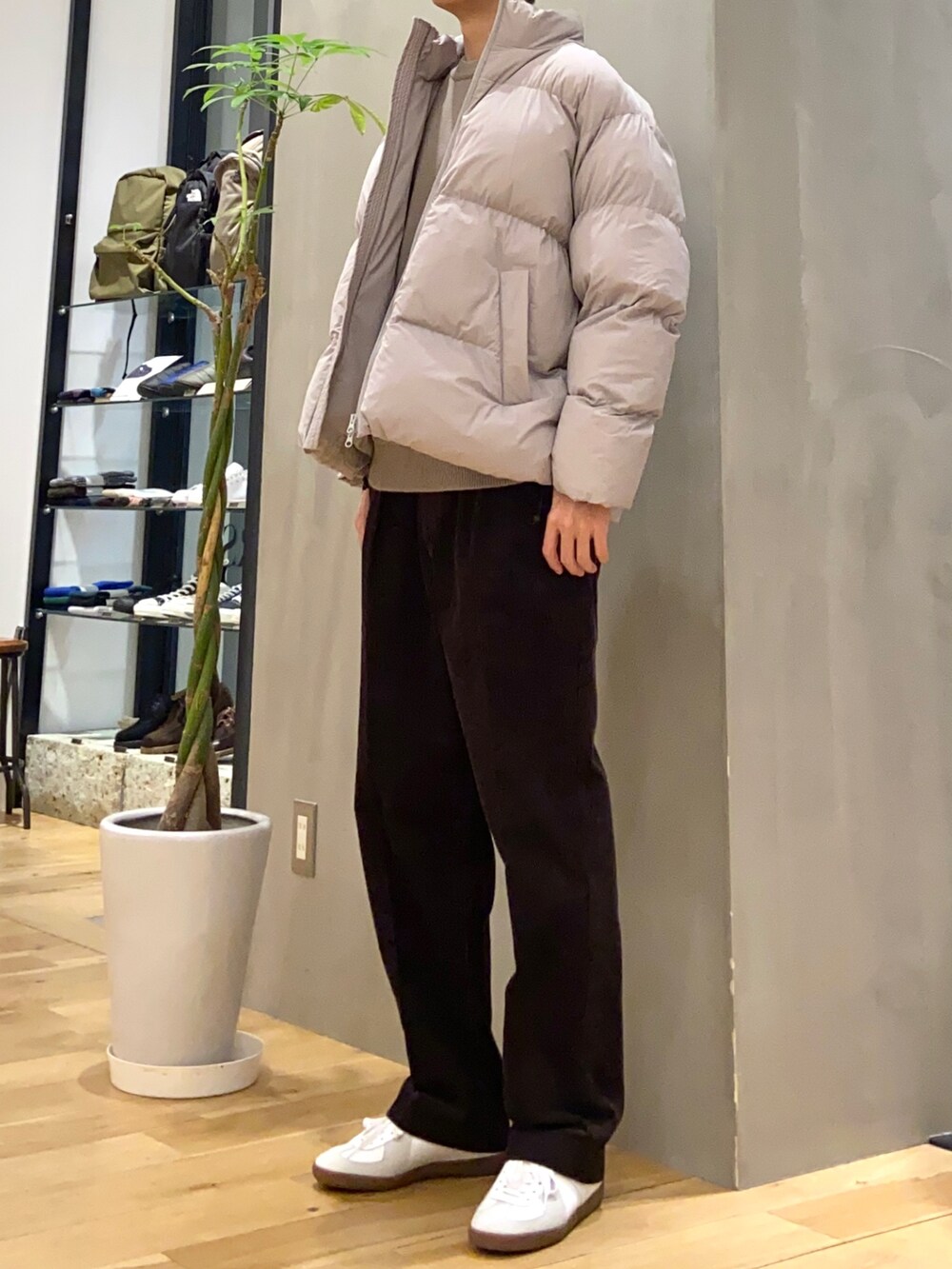 グレー系のダウンジャケット/コート、ブラウン系のニット/セーター、ホワイト系のスニーカーを着用したメンズの冬コーディネートの4枚目の写真
