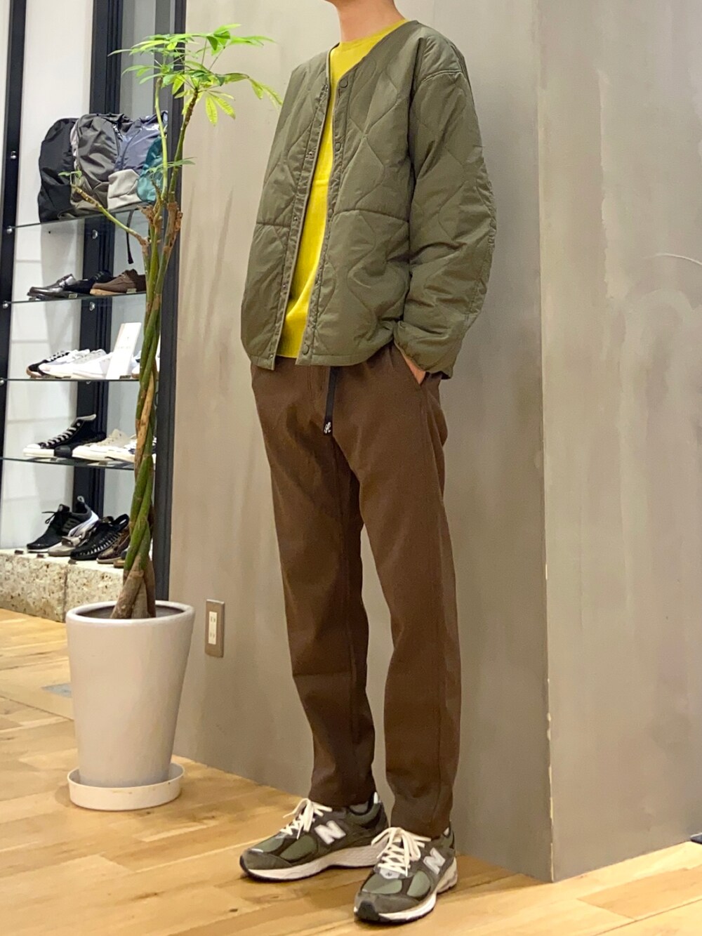 グリーン系のダウンジャケット/コート、イエロー系のニット/セーター、ブラウン系のその他パンツを着用したメンズの秋コーディネートの2枚目の写真