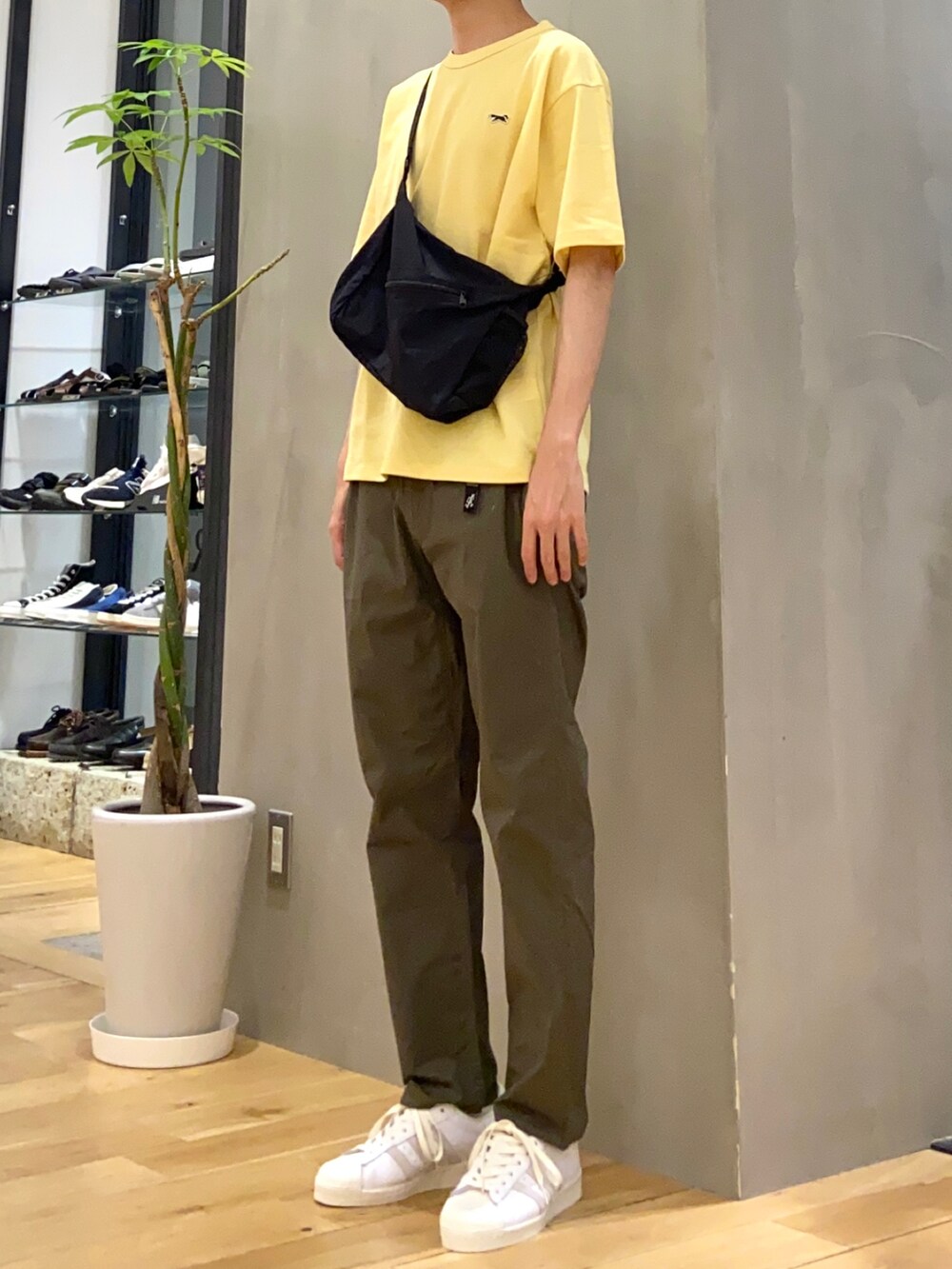 イエロー系のTシャツ/カットソー、ブラック系のショルダーバッグ、グリーン系のその他パンツを着用したメンズの春コーディネートの2枚目の写真